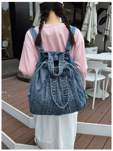 Vue détaillée d'un sac à dos en denim lavé avec fermeture à cordon et multiples lanières.