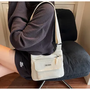 Detailansicht der lässigen weißen Umhängetasche mit mehreren Taschen und verstellbarem Gurt.