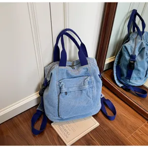 Washed denim backpack detail showing texture, dual handles and front pocket design.