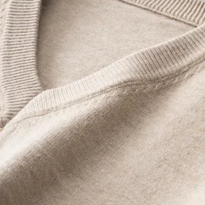 Close-up view of a cozy V-neck knit sweater collar, showing soft beige texture and fine ribbed trim.