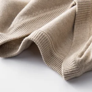 Beige V-neck knit sweater fabric detail showing soft texture and fine ribbed hem close-up.