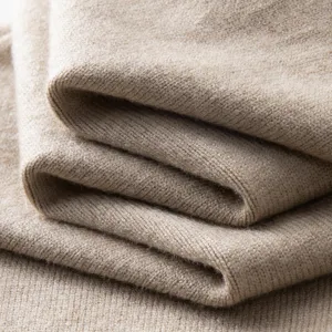 Close-up detail shot of soft cashmere knit sweater fabric texture in solid khaki color.