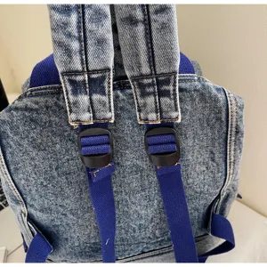 Detailed view of the washed denim backpack back straps and adjustable buckle close-up.
