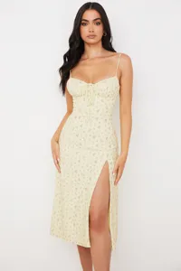 Close-up detail of the yellow floral spaghetti strap dress showcasing the front slit design.