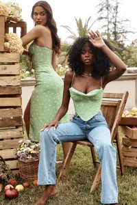 Outdoor fashion detail shot featuring green floral camisole dress and chic corset top style.