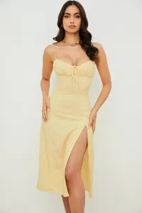 Close-up detail of the yellow floral slip dress featuring front slit and ruched bust.