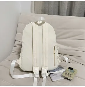 Vista detallada de la mochila de lona blanca para estudiantes con tirantes y bolsillo.