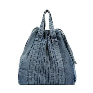 Détail en gros plan du sac à dos en denim lavé avec cordon, texture et lanières verticales.