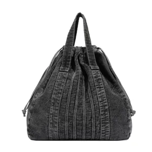 Vue détaillée du sac porté épaule en denim délavé foncé avec cordon et plis verticaux.