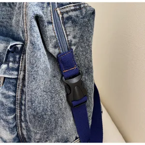 Close-up detail of women washed denim backpack showing texture zipper and blue strap hardware.