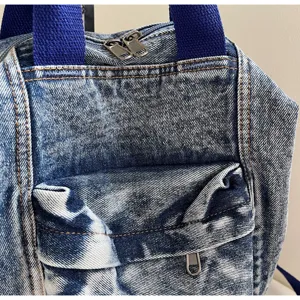 Washed denim backpack detail view showcasing premium fabric texture and durable metal zippers.