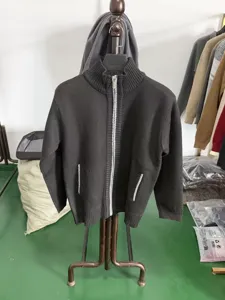 Vue détaillée d'un gilet zippé en tricot gris foncé pour homme sur un support de présentation.