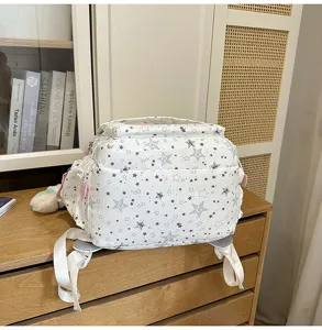 Vue détaillée du sac à dos d'étudiant blanc avec motif d'étoiles grises sur bureau.