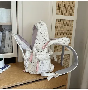 Vue rapprochée détaillée du sac à dos scolaire blanc à motif d'étoiles avec poches.