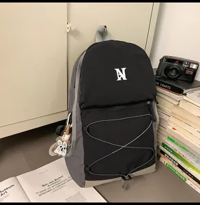Detailansicht des schwarz-grauen Freizeitrucksacks mit Bungee-Kordel und Charmanhänger.