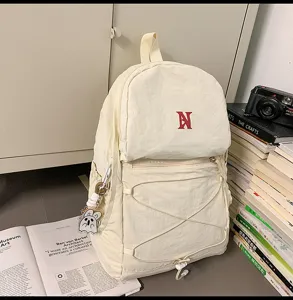 Minimalistischer beige Rucksack mit Kordelzug und süßem Anhänger für den täglichen Gebrauch.