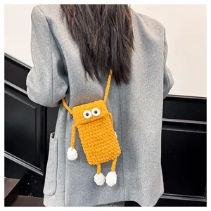 Detailed view of cute yellow knitted phone bag featuring big googly eyes and fun limbs.