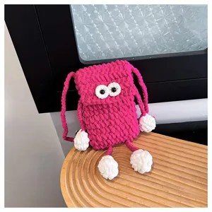 Detailed shot of cute handmade crochet pink phone bag with big googly eyes and shoulder strap.