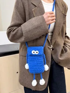 Handmade blue knitted phone bag with cute big eyes and limbs, stylish cross-body bag for women.