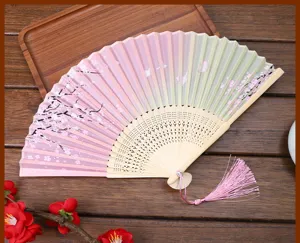 Gros plan sur les détails d'un éventail pliable avec motif de fleurs de cerisier.