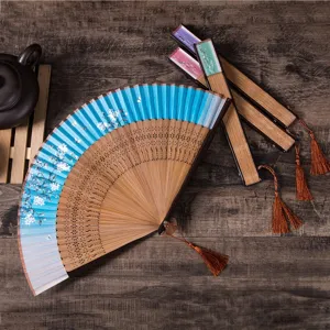 Traditional Japanese folding fan with cherry blossom pattern, wooden hollow carved ribs and tassel.