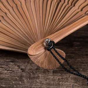 Close-up of bamboo folding fan detail, featuring fine wood texture and black lanyard handle.