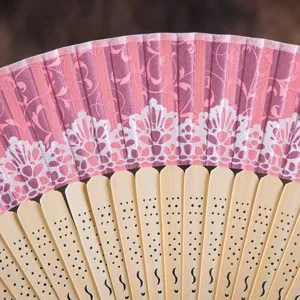 Exquisite closeup view of the pink lace folding hand fan with carved bamboo ribs.