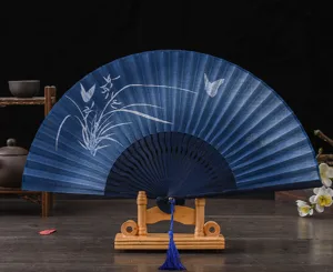 Traditional blue folding fan with elegant butterfly floral pattern and wooden display stand.