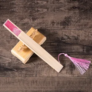 Close-up of elegant folding fan with pink lace pattern and matching tassel on wood stand.