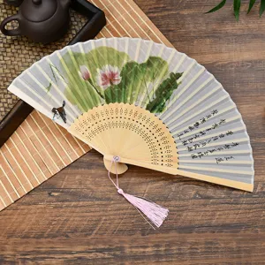 Detailed shot of Chinese folding hand fan with lotus painting, silk surface and bamboo ribs.