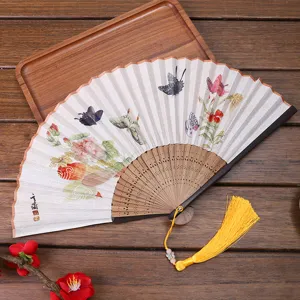 Detail shot of Chinese traditional linen folding fan with butterfly floral pattern and tassel.