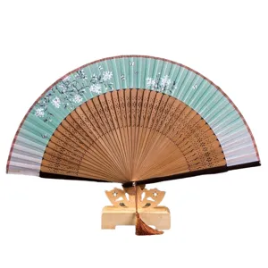 Traditional Japanese style folding hand fan with elegant cherry blossom pattern and wooden stand.