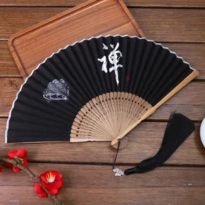Chinese style folding fan with black fabric, wooden ribs, Zen calligraphy and tassel.