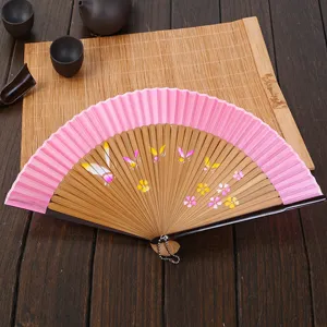 Women folding fan with pink fabric and bamboo ribs, featuring painted butterfly and floral design.