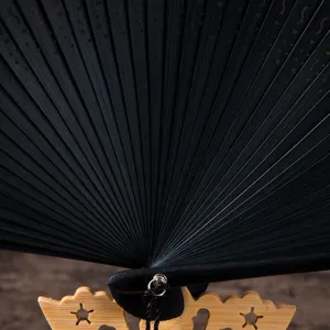 Detailed view of black folding fan rib structure with carved wooden stand, vintage style.
