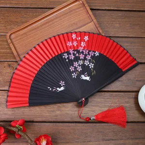 Traditional folding hand fan detail shot featuring cherry blossom rabbit design with tassel.
