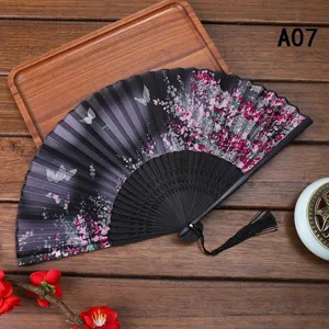 Detalle de abanico plegable de seda japonesa con patrón de flor de cerezo y borla negra.