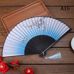 Gros plan sur l'éventail pliant traditionnel avec motif de fleurs de prunier et pompon.