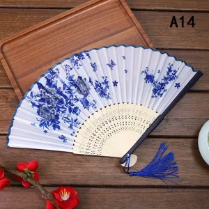Vista detallada de abanico plegable de bambú con motivo floral azul y borla elegante.