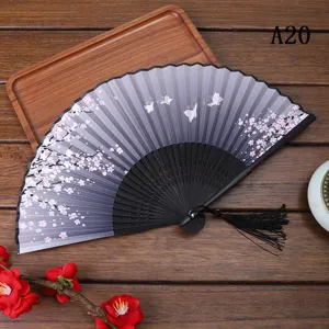 Éventail pliant de style chinois avec motif de fleurs de cerisier et pompon noir.