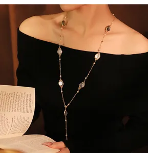 Dettaglio di una lunga collana elegante con perle naturali e dettagli in madreperla.