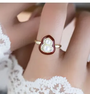 Nahaufnahme eines eleganten roten Emaille Doppelkürbis Perlenrings mit funkelnden Zirkoniasteinen.