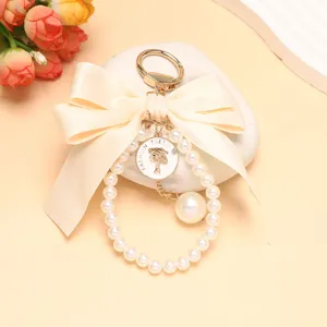 Elegante portachiavi con perle e fiocco dorato, ciondolo chic per borse alla moda.
