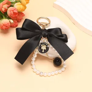 Squisito ciondolo portachiavi con perle e fiocco nero, elegante accessorio per borsa.