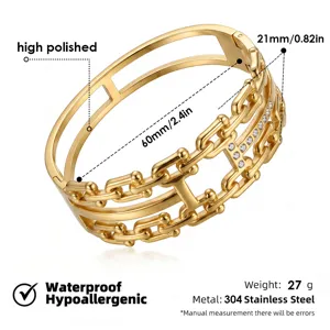 Pulsera rígida de acero dorado con cadena ancha y diseño H de cristal brillante.