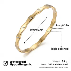Pulsera rígida de acero inoxidable dorado ondulado con cristales brillantes elegantes.