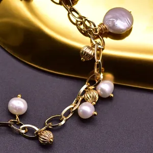 Close-up of a gold chain bracelet adorned with natural freshwater pearls and golden beads.