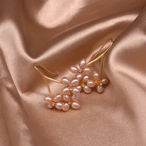 Close-up detail of handmade freshwater purple pearl flower earrings with rhinestones.