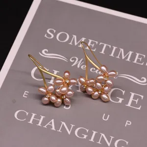 Close-up detail of handcrafted freshwater pearl flower earrings with elegant gold hooks and crystals.