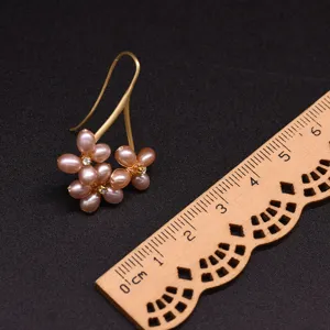 Detail view of freshwater purple pearl flower earring close up with scale wooden ruler.